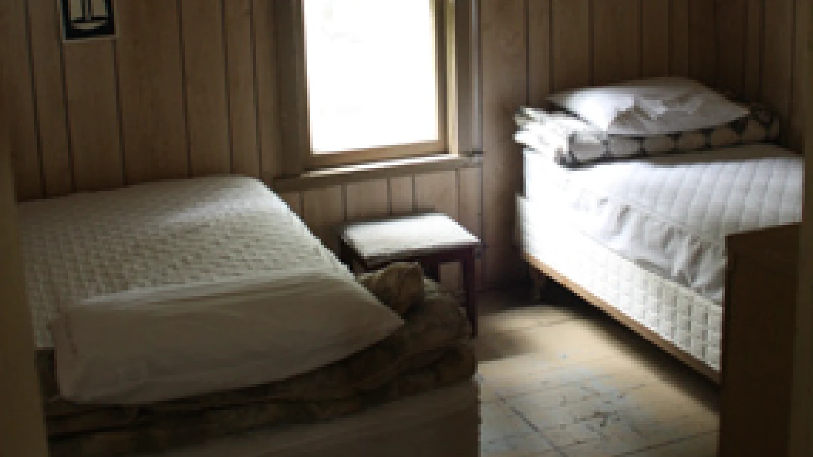 Pigeon Lake Resort Cottage Two.&nbsp; Bedroom with a bed beside a window in a cottage interior.